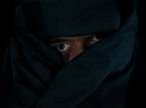 Scary Eyes Behind Black Cloak in the Darkness
