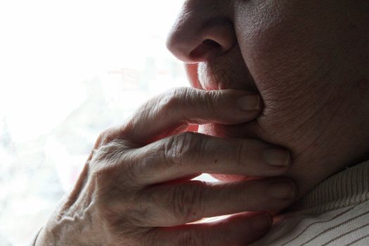 Hand over mouth of elderly woman wondering