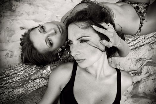 Two lovely girls in swimsuits lying on the beach