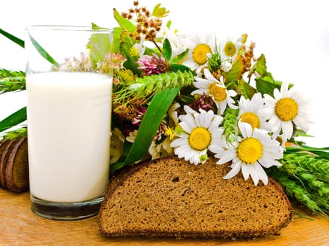Photo of the bread milk and camomile at wooden board against the white background  