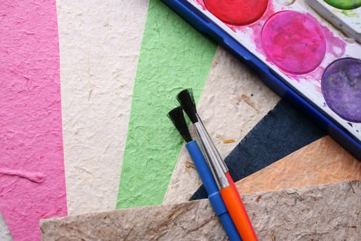 Paint Brushes, Paint and different colored handmade paper