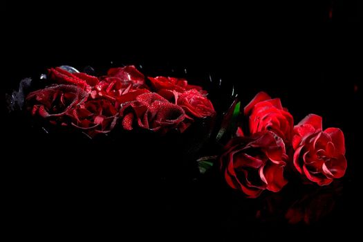 Red roses with water drops on black 