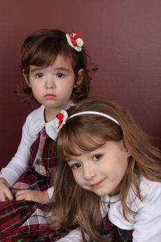 Two cute little sisters wearing Christmas dresses