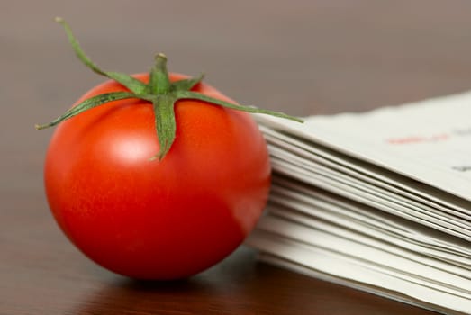 Red tomato on a table with a newspapper