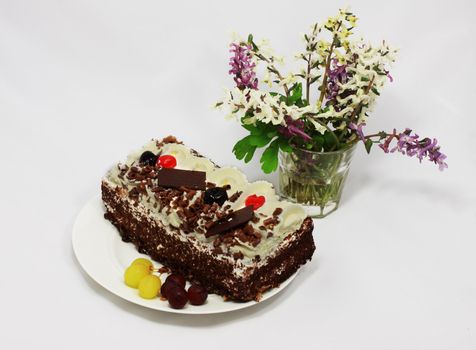delicious cake with fruits, cream and bouquet of flowers nearby