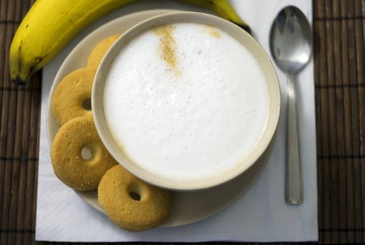 A cup of coffe and a metal spoon on wooden table