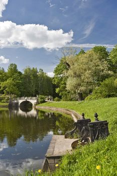 Park with river and old bridge in sunny summer day