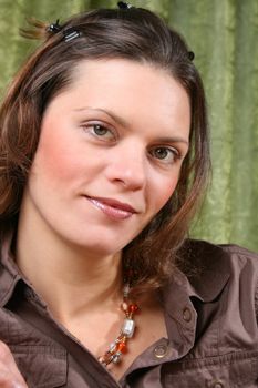 Beautiful brunette female wearing a brown shirt against a green background