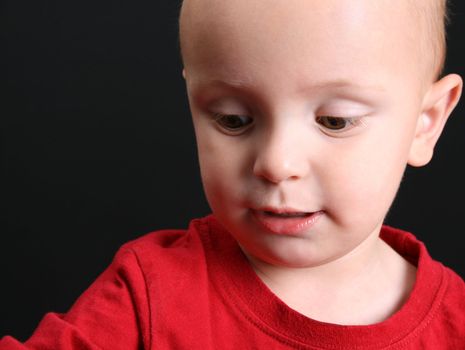 Blond toddler against a black background with a serious expression
