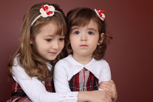 Two cute little sisters wearing Christmas dresses