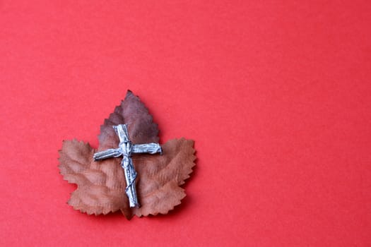 Autumn leaf with a silver cross on a red background
Leather bound bible opened at a piece of scripture