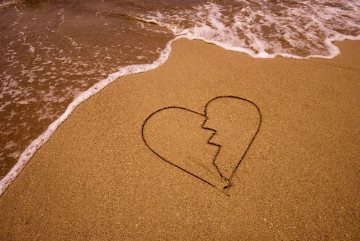 Broken heart drawing in sand on the seashore