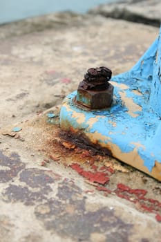 Rusted old bolt and screw on a blue lamp post foot