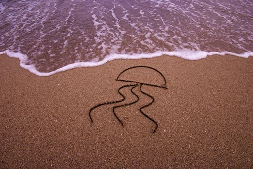 Jellyfish symbol drawn in sand on the beach