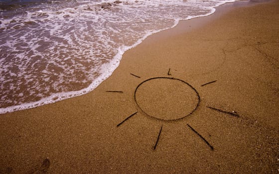 Sun drawn in sand on beach