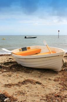 White and Yellow boat on sandy beach. Beach with washed up seaweed, sea horizon in background. Location Christchurch, Dorset UK.