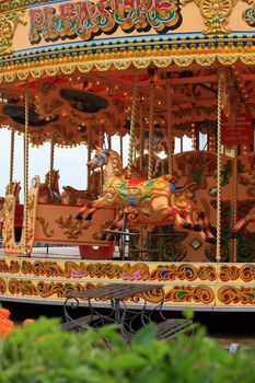 A colourful fairground carousell ride with colourful carved horses, located on the pier at Weymouth, Dorest UK. 