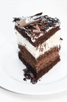 Close up detail of a slice/wedge of chocolate gateaux set on a white oval plate.