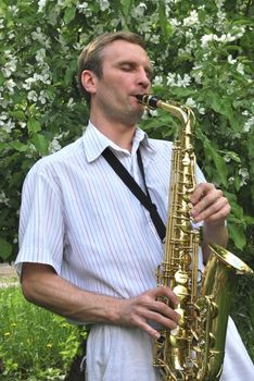 the  man with saxophone on the background of the flowering tree