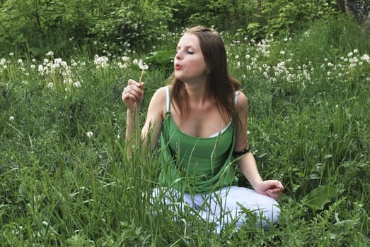 beautiful girl  on summer lawn with dandelions