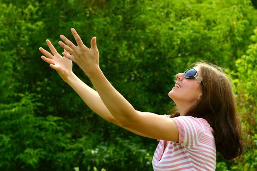 The girl on the summer meadow, stretching hands to the sky