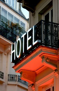 Hotel sign in Latin Quarter of Paris France with orange neon glow underneath.