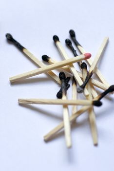 a pile of burnt matches with one head still unburned
