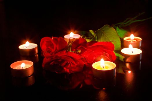 Red roses with candles on black