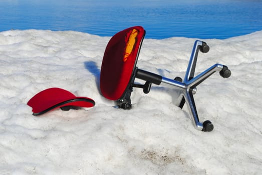 An abandoned office chair lying in snow.