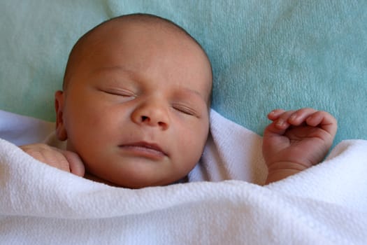 Week old baby boy on a blue blanket early in the morning