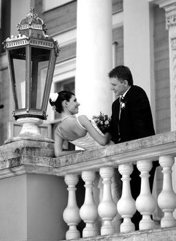 Happy newlywed couple leaning on hotel honeymoon balcony.