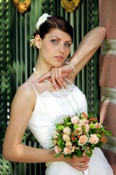 Half body portrait of beautiful young adult bride in white dress holding bouquet of flowers.