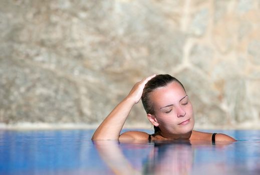 Young beautiful woman cools off in a pool during a hot summer afternoon