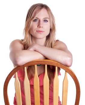 A girl sits backwards on a chair with her arms crossed.
