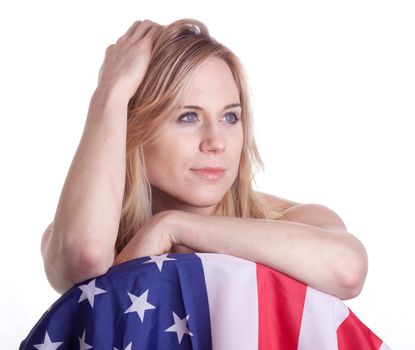 A cute girl poses with an American Flag.  Her hand is in her hair.