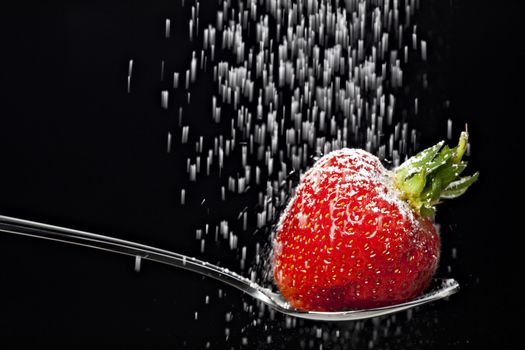 icing sugar falling on a strawberry on a spoon