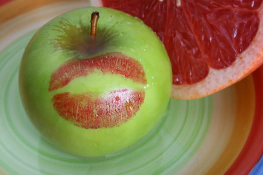 Sliced Pomelo and a green apple with a red kiss