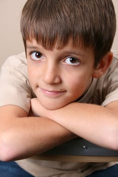 Young boy with big eyes, resting on a chair back