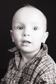 Serious blond toddler against a black background 