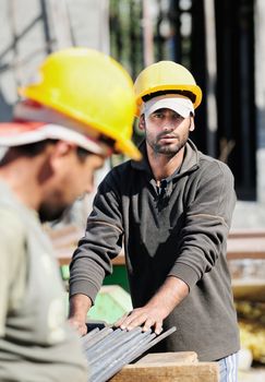 Two authentic construction workers, one of them looking at camera