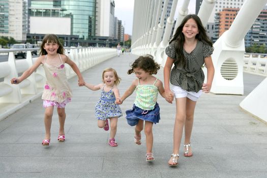Four little girl group walking in the city bridge downtown buildings