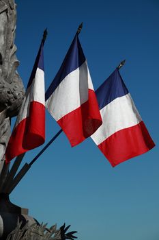 Three French tricolours adorn a war memorial in SW France