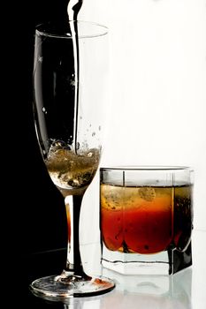 Glass of champagne and whisky with ice. A black and white background.