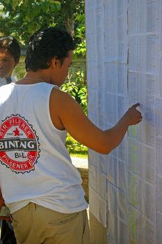 A young man searching for his name on a registration list on the day of the Presidential election. Tuban Bali, Indonesia. July 8, 2009.