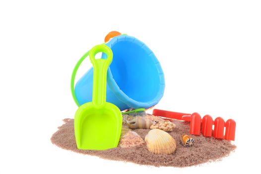 Colorful beach toys in the sand with sea shells.