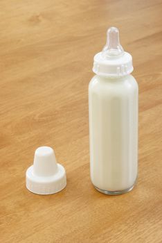 A baby bottle full of milk, sitting on the table.