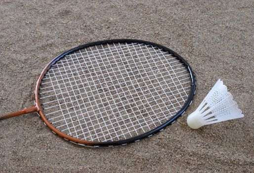 Badminton equipment lying on the sand at the beach.