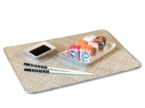 sushi, soya sauce, chopsticks are located on bamboo mat
