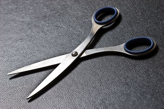Photo of blue scissors on texture imitation leather