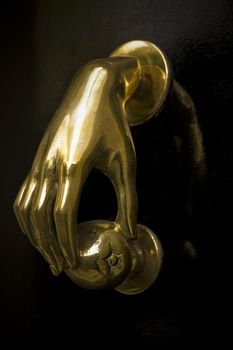 Bronze Door knocker in the shape of a hand holding an apple, picture taken in Manchester UK
